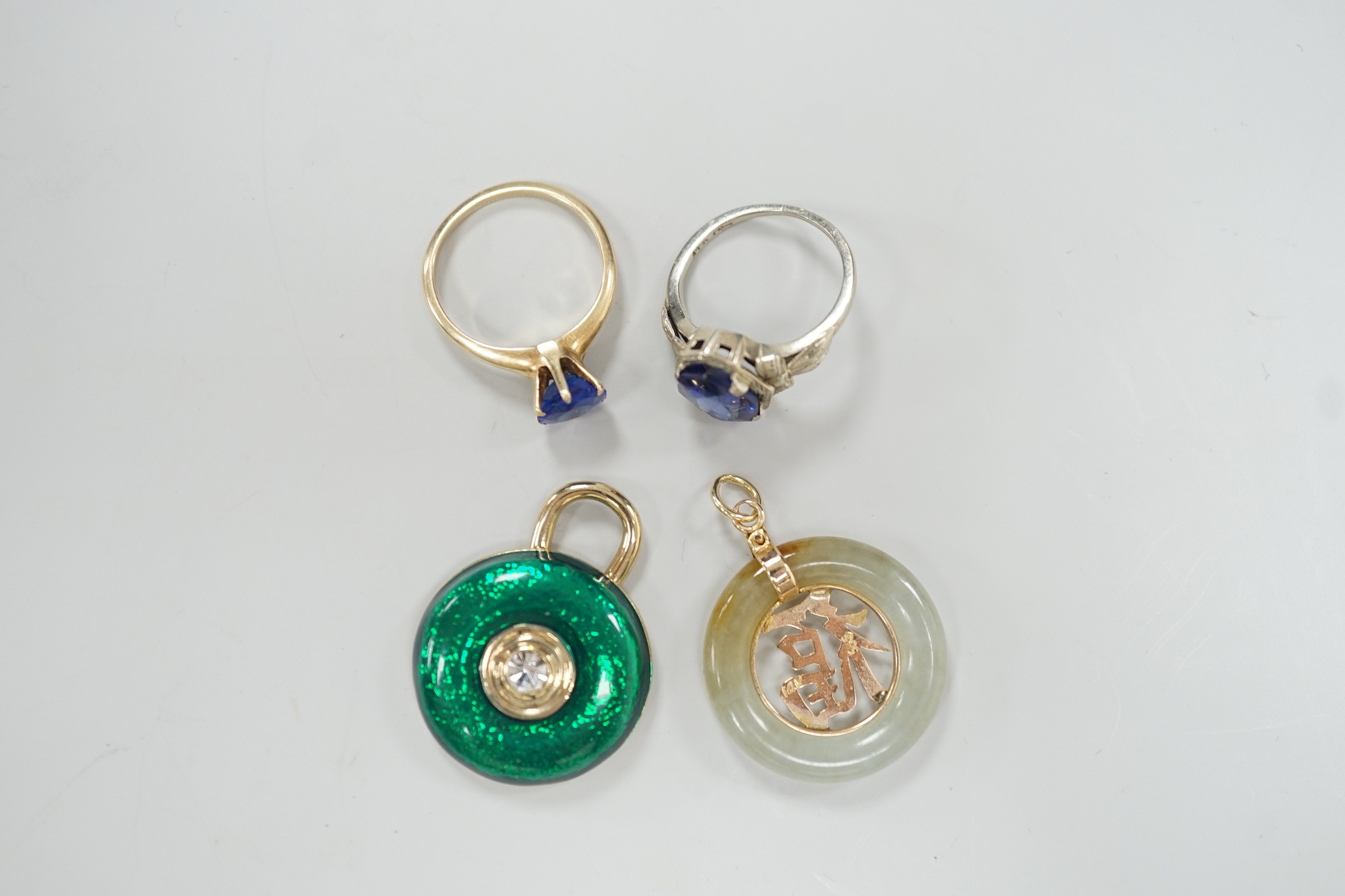 A 14k white metal and oval cut synthetic sapphire ring, a yellow metal and blue paste ring, a 585 yellow metal and jadeite pendant and a costume pendant.